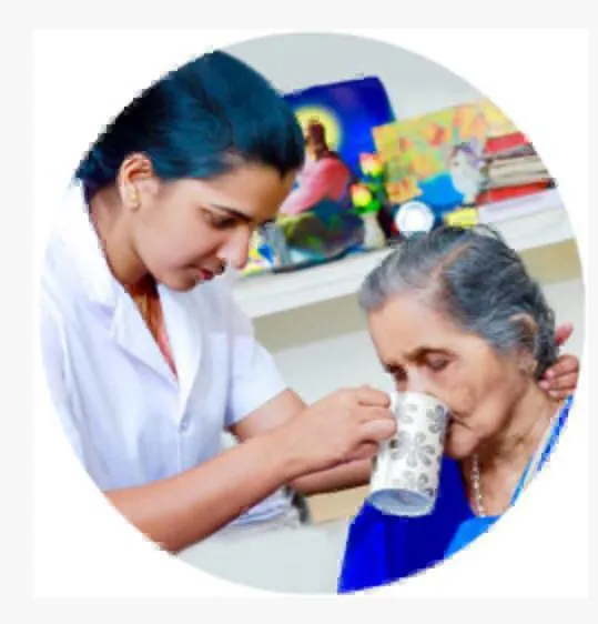 Nurse assisting elderly woman with feeding support in Bangalore